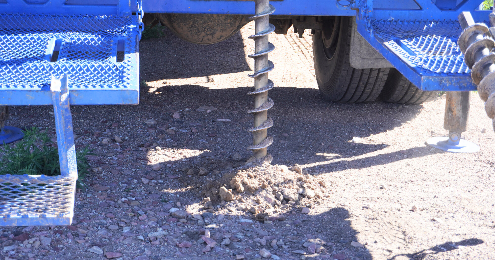 JB Drilling drill in the ground with blue JB Drilling truck in the background