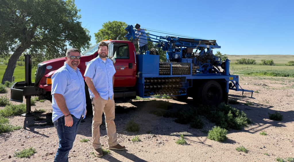 Brothers Jared and Mathias Jung pose with the JB Drilling drill in the background